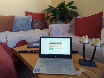a sofa table with a laptop, candles, a flute and a book